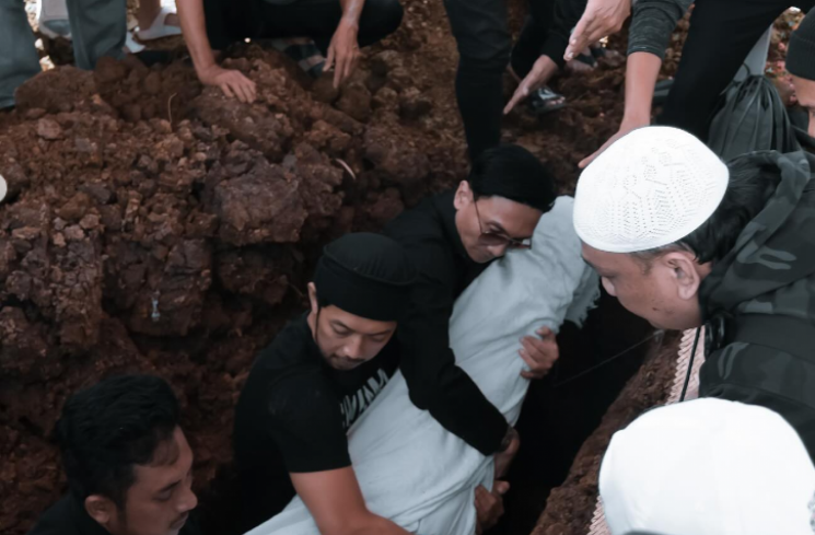 Anji (pakai kacamata hitam) ikut turun ke liang lahat saat prosesi pemakaman ayahnya, Hartiyo. [Instagram @duniamanji]
