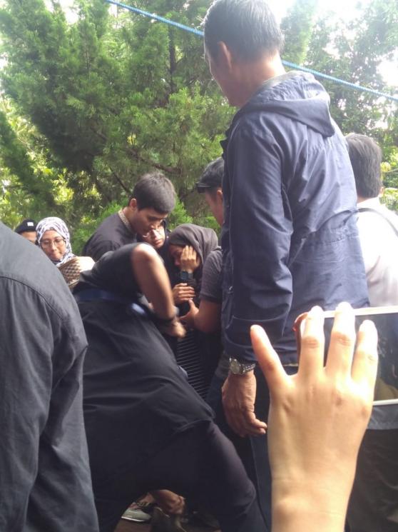 Dewi Sartika terlihat lemas saat melihat jenazah Andi Seventeen dikuburkan di TPU Glagahsari, Selasa (25/12/2018). (Matamata.com/Uni Irmagani)