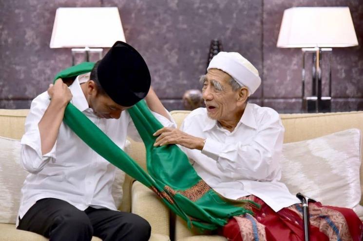 Kiai Maimoen Zubair kalungkan sorban hijau ke leher Presiden Jokowi. [Instagram]