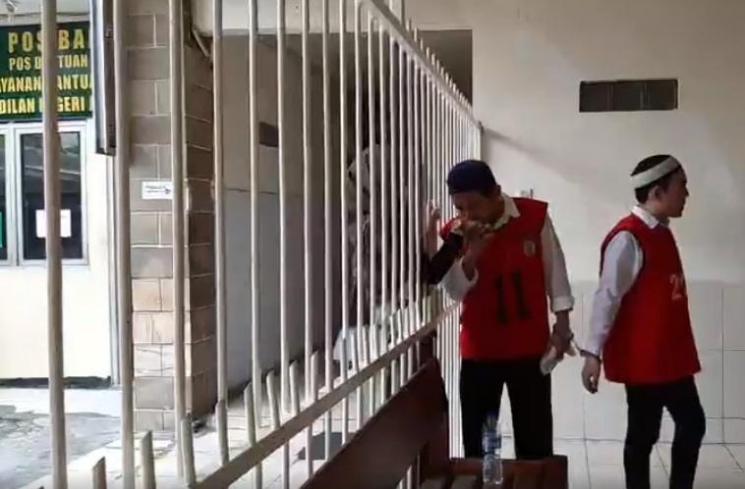 Zul Zivilia mencium tangan istrinya, Retno Paradinah dari balik jeruji besi. (Matamata.com)