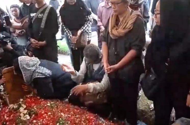 Dewi Irawan cium nisan Ade Irawan. (Matamata.com)