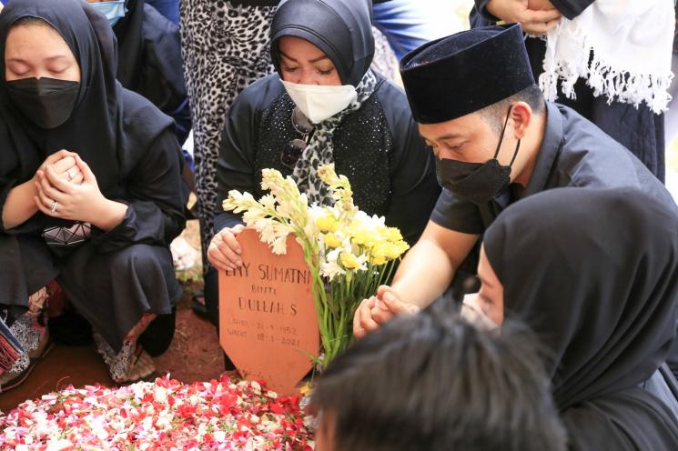 Komedian Denny Cagur berdoa di atas pusara ibunya setelah dimakamkan di TPU Tipar, Depok, Jawa Barat, Selasa (19/1/2021). [Matamata.com/Alfian Winanto]