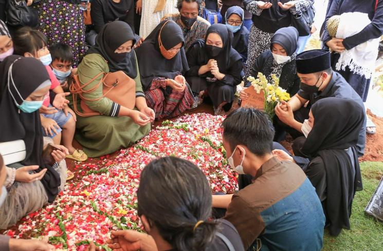 Komedian Denny Cagur berdoa di atas pusara ibunya setelah dimakamkan di TPU Tipar, Depok, Jawa Barat, Selasa (19/1/2021). [Matamata.com/Alfian Winanto]
