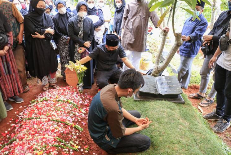 Komedian Denny Cagur berdoa di atas pusara ibunya setelah dimakamkan di TPU Tipar, Depok, Jawa Barat, Selasa (19/1/2021). [Matamata.com/Alfian Winanto]