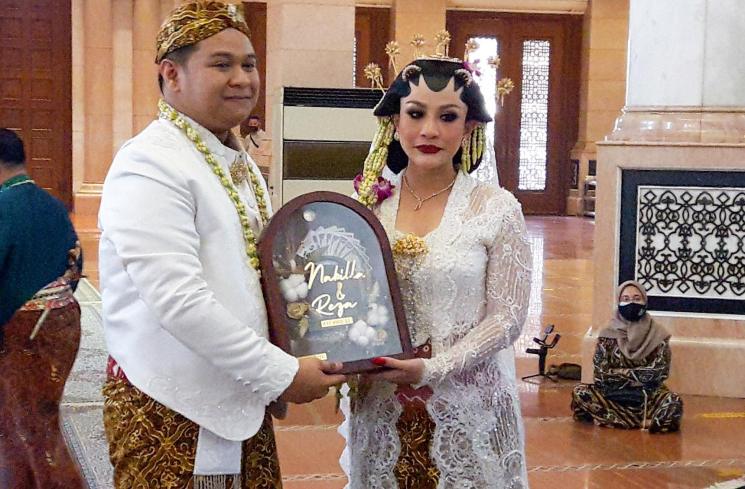 Nabilla Gomes dan suaminya, Muhammad Reza memamerkan cincin di jari manis mereka usai melangsungkan akad nikah di Masjid Kubah Emas, Depok, Jawa Barat, Jumat (28/5/2021). [MataMata.com/Alfian Winanto]