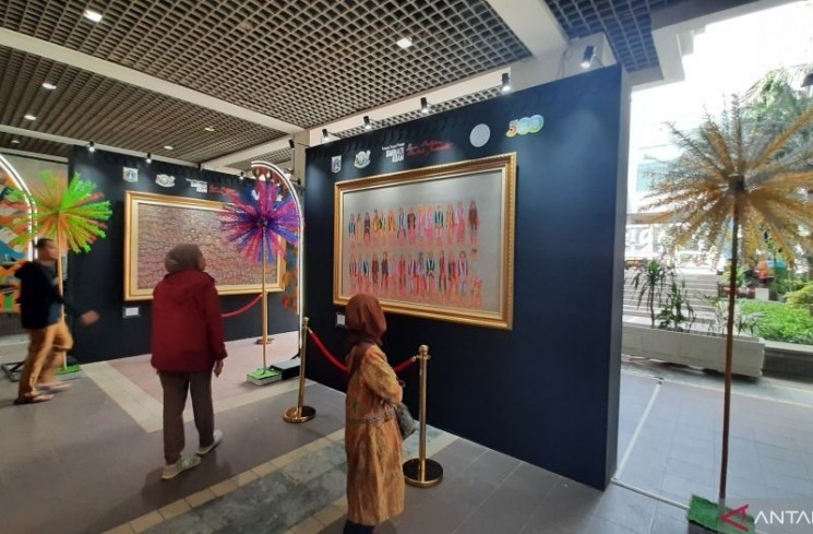 Dua orang melihat salah satu karya lukis seniman Betawi Sarnadi Adam bertema 